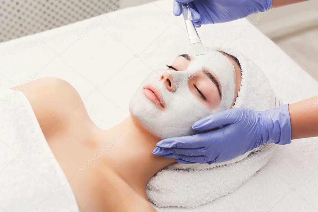 Woman gets face mask by beautician at spa