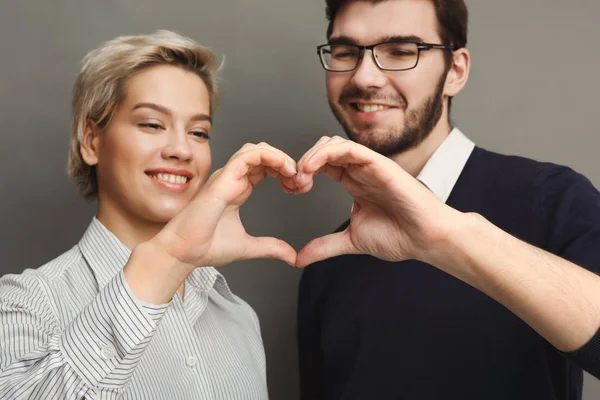 Pareja feliz enamorada mostrando el corazón con sus dedos — Foto de Stock