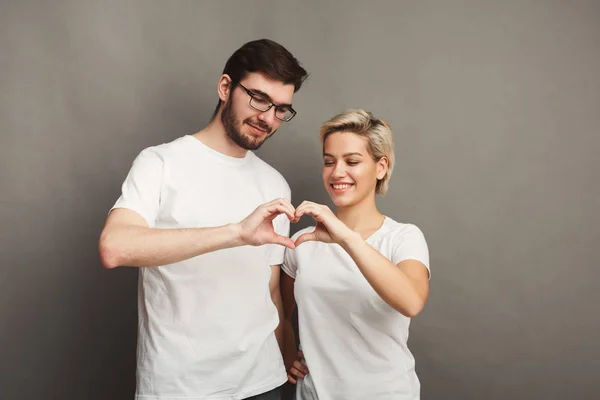 Pareja feliz enamorada mostrando el corazón con sus dedos — Foto de Stock