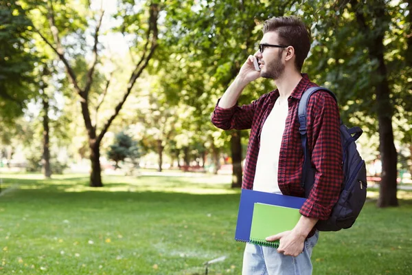 Jovem estudante falando no smartphone no parque — Fotografia de Stock