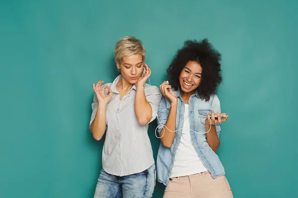 Twee vrouwen luisteren van muziek en het delen van oortelefoons — Stockfoto