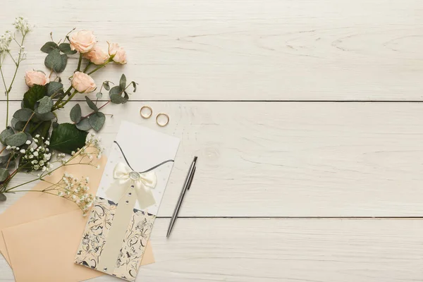 Tarjetas de invitación de boda y sobres en mesa de madera blanca, vista superior —  Fotos de Stock