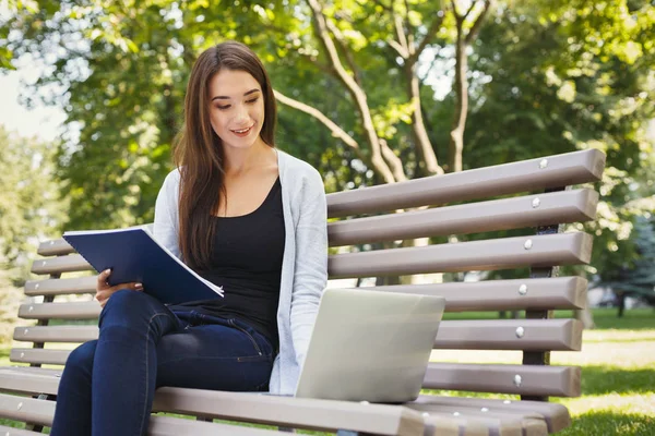 Dizüstü bilgisayar kullanarak parkta oturan gülümseyen öğrenci kız — Stok fotoğraf