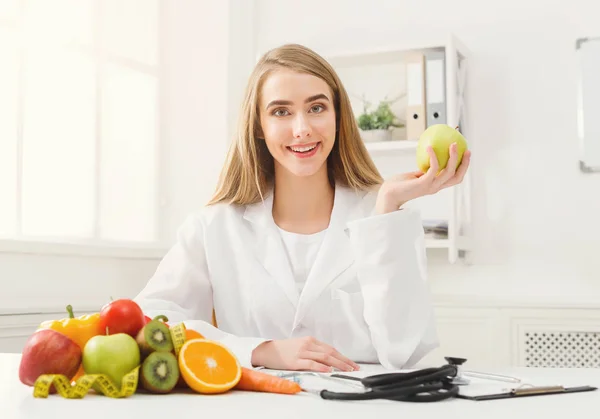 Donna nutrizionista sorridente con mela in ufficio — Foto Stock