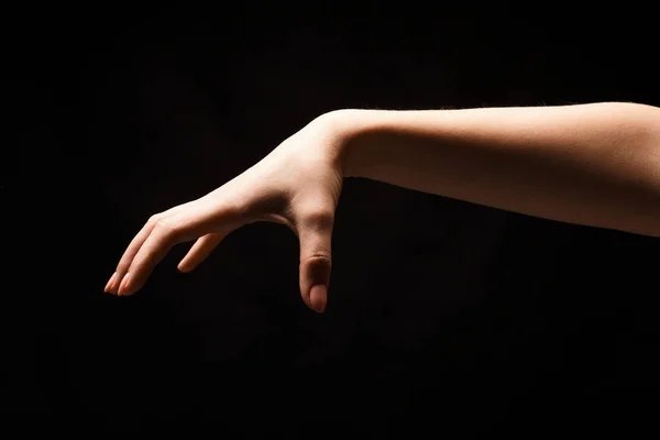 Vrouwelijke hand oppakken van iets, knipsel op zwart — Stockfoto