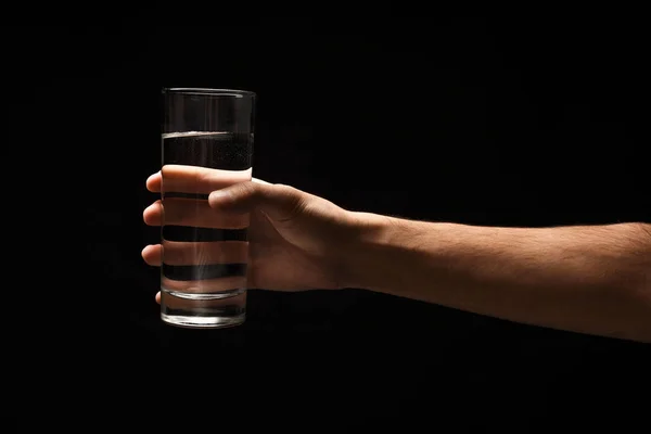 Tangan laki-laki memegang kaca air terisolasi pada hitam — Stok Foto