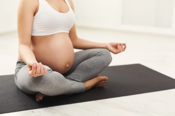 Mujer embarazada irreconocible entrenando yoga en pose de loto — Foto de Stock