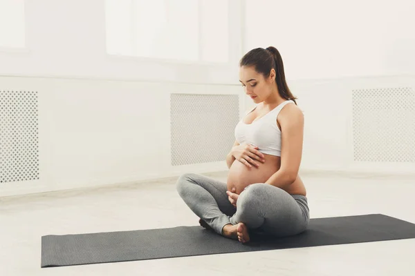 Mujer embarazada acariciando su vientre en casa — Foto de Stock