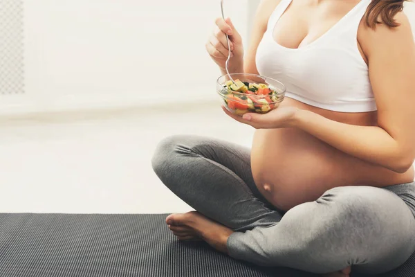 Неузнаваемая беременная женщина ест свежий зеленый салат — стоковое фото