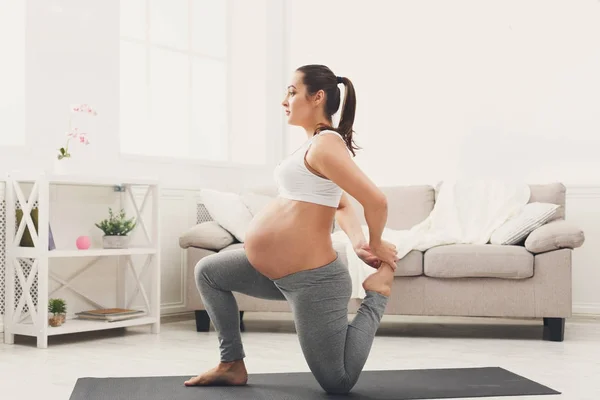 Счастливая беременная женщина тренирует йогу дома — стоковое фото
