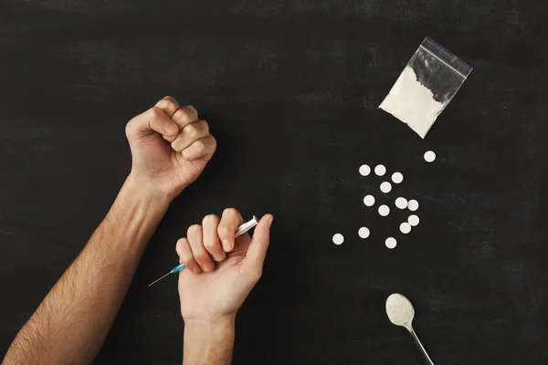 Drug addict hands holding syringe for injection on dark table — Stock Photo, Image