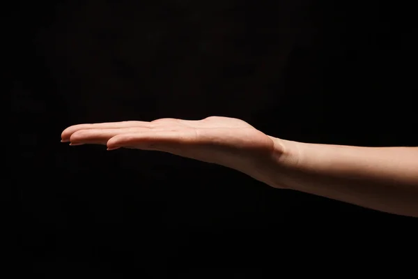 Frau hält Handfläche offen isoliert auf schwarz — Stockfoto