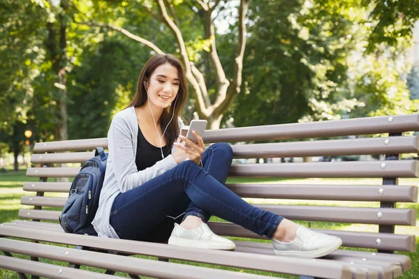 Estudiante sentado en el parque y usando smartphone — Foto de Stock