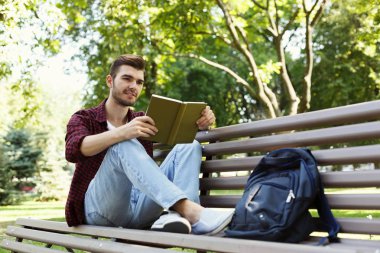 Genç adam park kopya alanı içinde kitap okumak