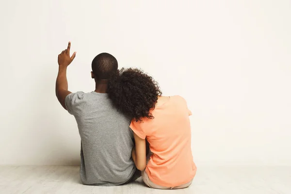 Afro-amerikanska paret tittar upp, sitter på golvet — Stockfoto