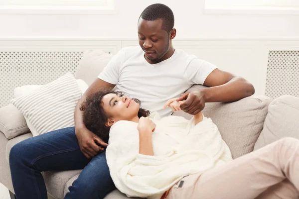 Glimlachend zwart paar rest gelet op de sofa thuis — Stockfoto