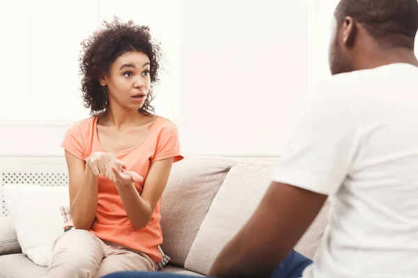 Emotional black couple drinking coffee on sofa at home — Stock Photo, Image