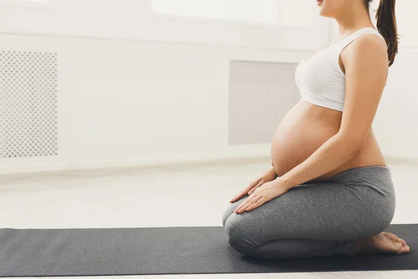 Unrecognizable pregnant woman training yoga in lotus pose — Stock Photo, Image