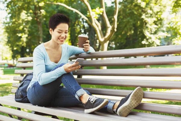 Mujer sonriente joven usando teléfono inteligente al aire libre — Foto de Stock