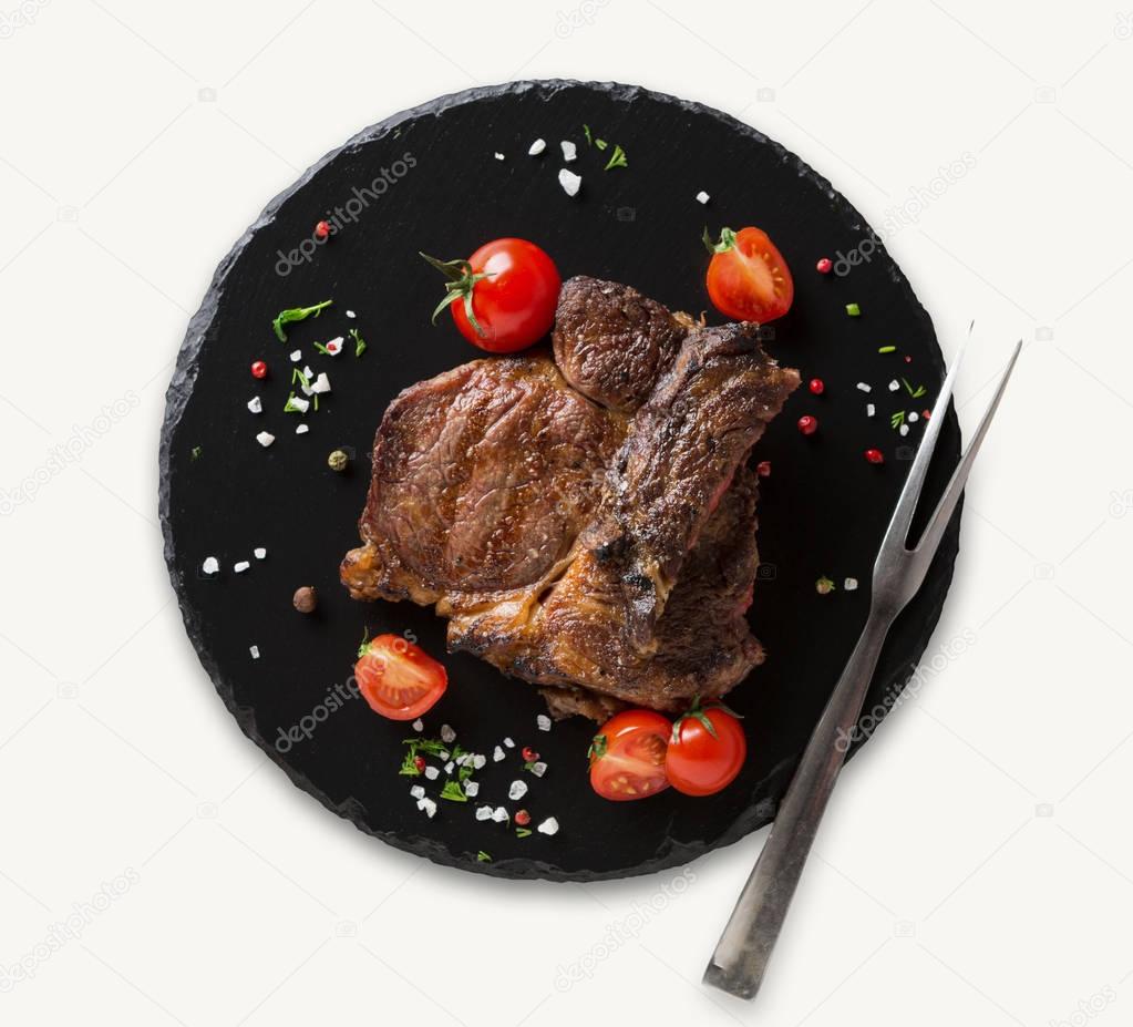 Rib eye steak on black plate, closeup, isolated