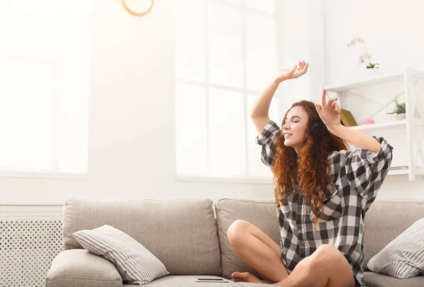 Mujer feliz con auriculares en el sofá — Foto de Stock