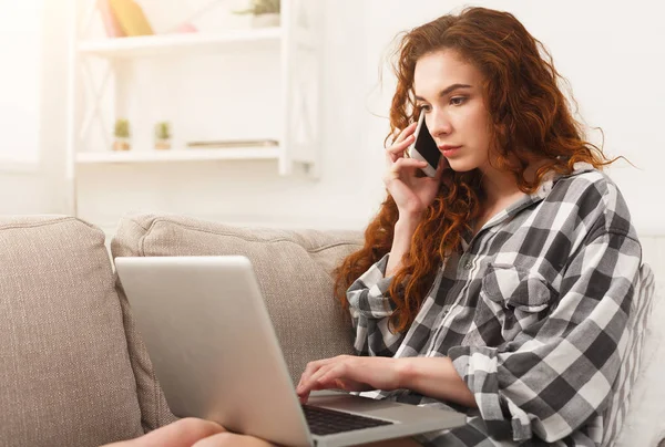 Menina com laptop e móvel sentado no sofá bege . — Fotografia de Stock