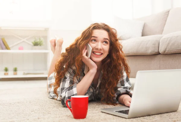 Menina com laptop e móvel deitado no chão — Fotografia de Stock