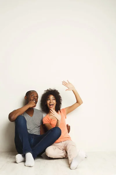 Casal afro-americano olhando para cima, sentado no chão — Fotografia de Stock