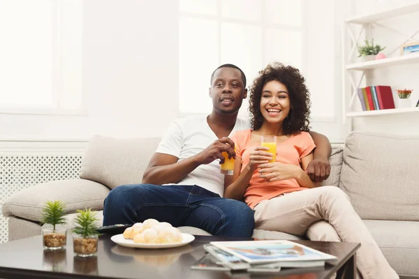 Sonriente pareja joven afroamericana viendo televisión en casa —  Fotos de Stock