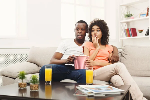 Surpris jeune couple afro-américain regarder la télévision à la maison — Photo