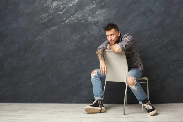 Knappe man zittend op de stoel en poseren in studio — Stockfoto