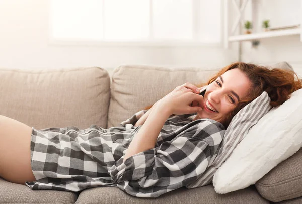 Young girl talking on mobile lying on beige couch — Stock Photo, Image