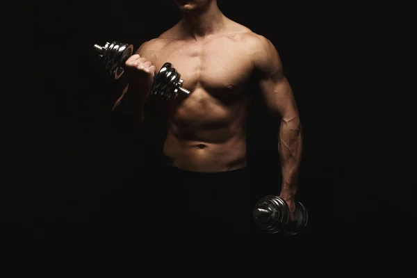 Сильный спортсмен с гантелями демонстрирует обнаженное мускулистое тело — стоковое фото