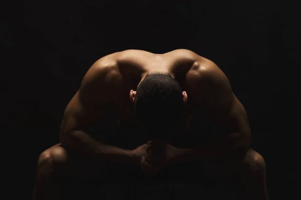 Mužské fitness model sedí u černé studio pozadí — Stock fotografie