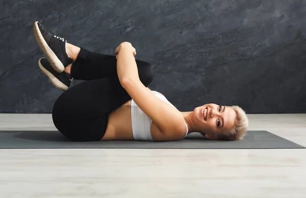 Gelukkig fitness vrouw uitrekken op grijze achtergrond binnenshuis — Stockfoto