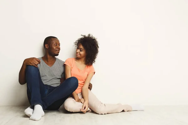 Afrikansk-amerikansk par kigger op, sidder på gulvet - Stock-foto