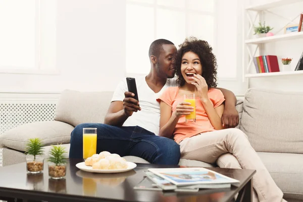 Sonriente pareja joven afroamericana viendo televisión en casa —  Fotos de Stock