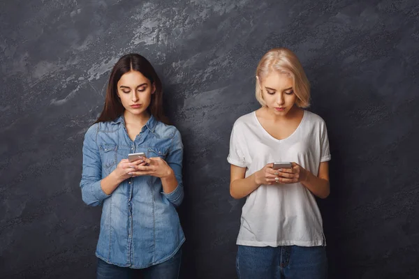 Δύο κορίτσια με smartphones που ψάχνει στα smartphones — Φωτογραφία Αρχείου
