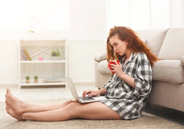Katta oturan dizüstü bilgisayar ile genç Kızıl saçlı kız — Stok fotoğraf