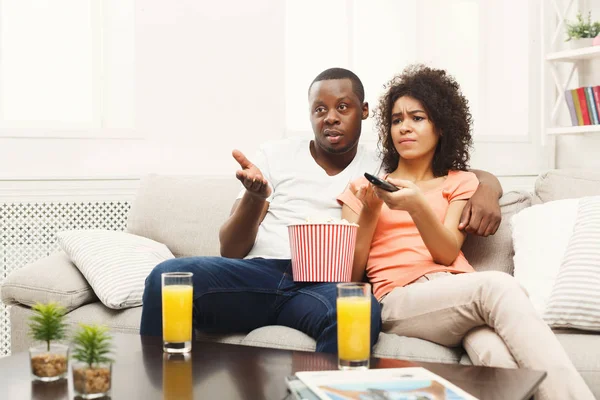 Pareja joven afroamericana infeliz viendo la televisión en casa —  Fotos de Stock