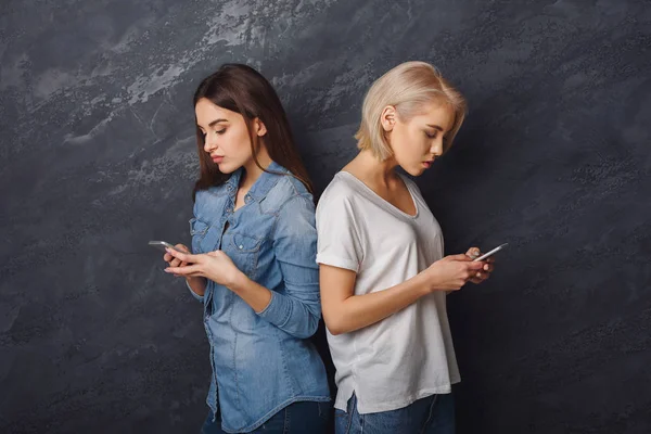 Duas meninas com smartphones à procura de smartphones — Fotografia de Stock