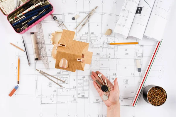 Architect holding keys at house model in office — Stock Photo, Image