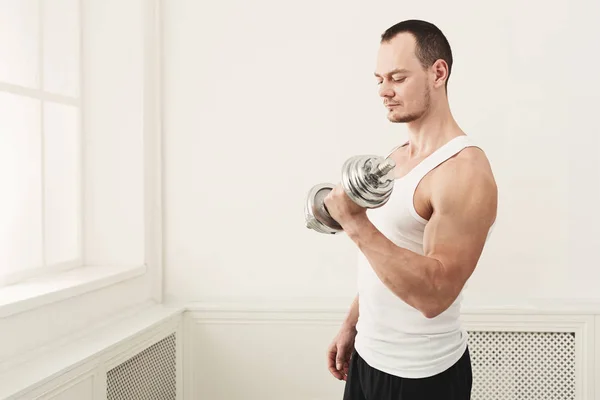 Hombre atlético fuerte con mancuerna muestra el cuerpo muscular —  Fotos de Stock