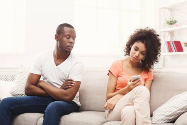 Afrikalı-Amerikalı çift evde, kız taxting smartphone cep telefonu ile