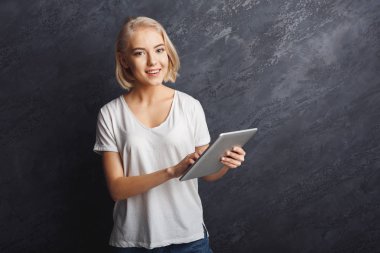 Gri zemin üzerine tablet ile gülümseyen kadın