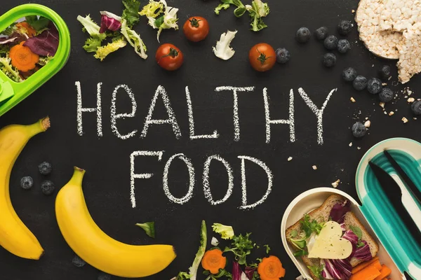 Lunch boxes filled with healthy food on black board — Stock Photo, Image