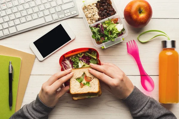 妇女吃健康三明治从午餐盒在她的工作桌 — 图库照片