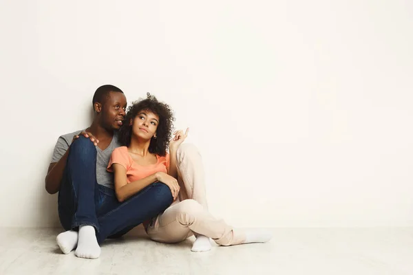 Afro-amerikanska paret tittar upp, sitter på golvet — Stockfoto