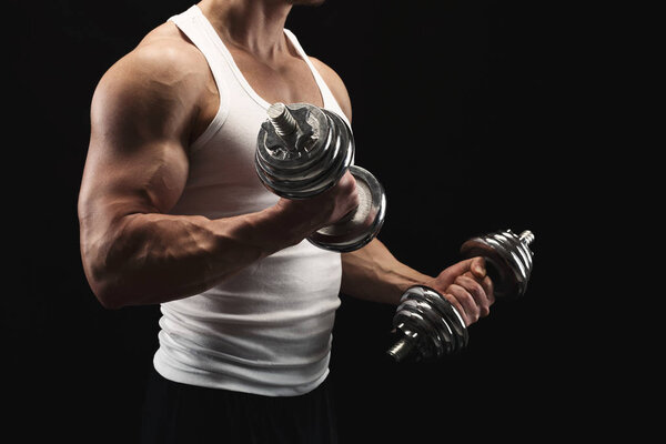 Strong athletic man with dumbbell showes muscular body
