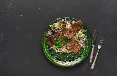 Üzerinde küçük domuz biftek salata ile siyah arka plan